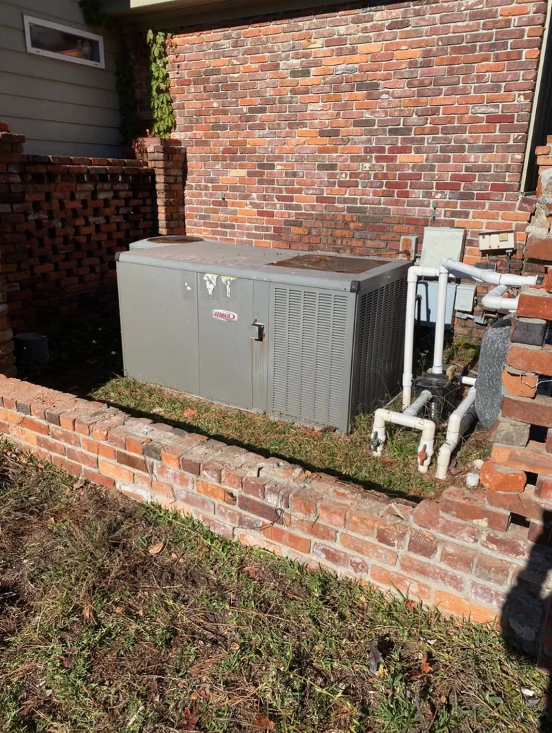 Original outdoor Lennox packaged HVAC unit inside a brick enclosure before replacement.